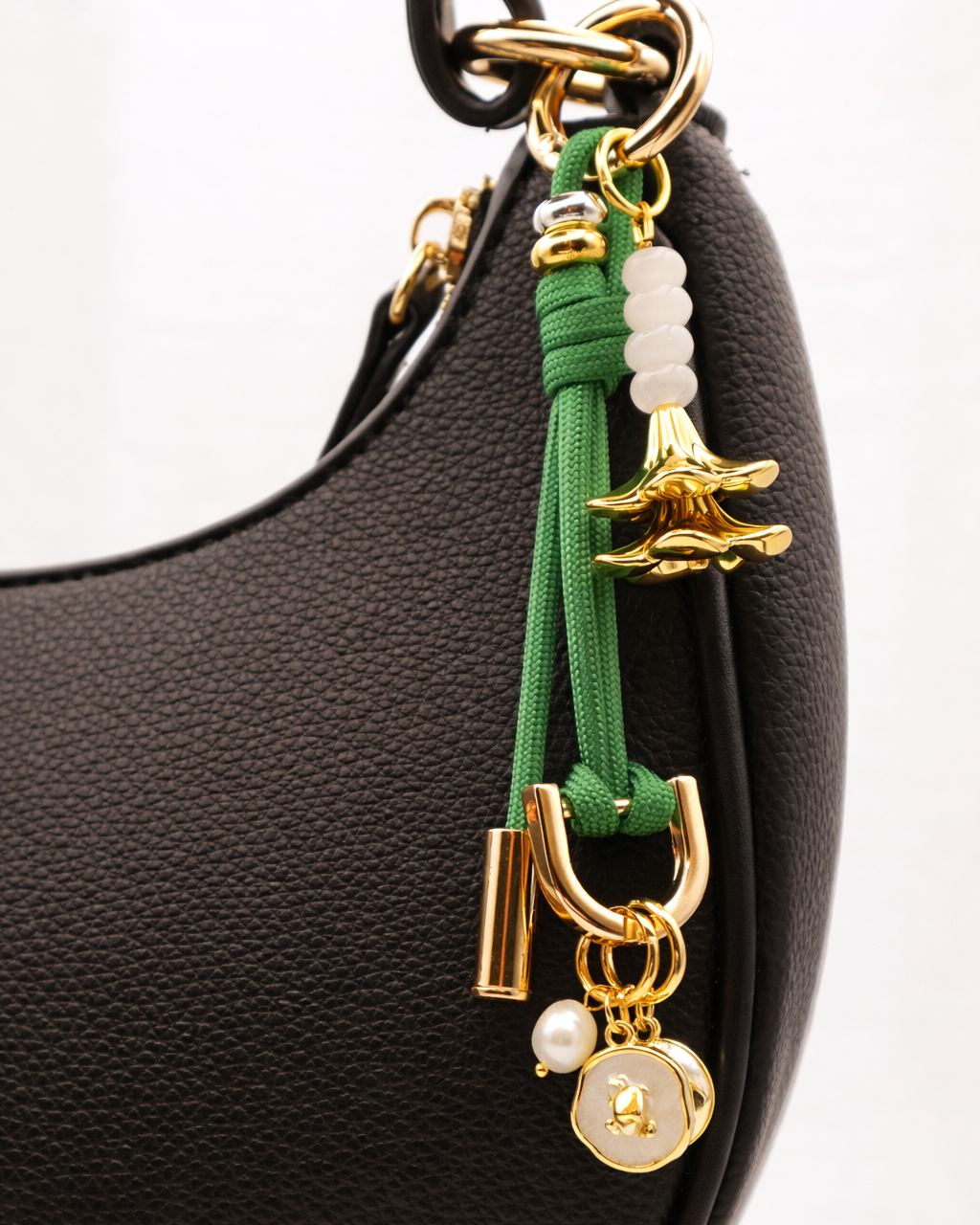 Black handbag with a green and gold charm