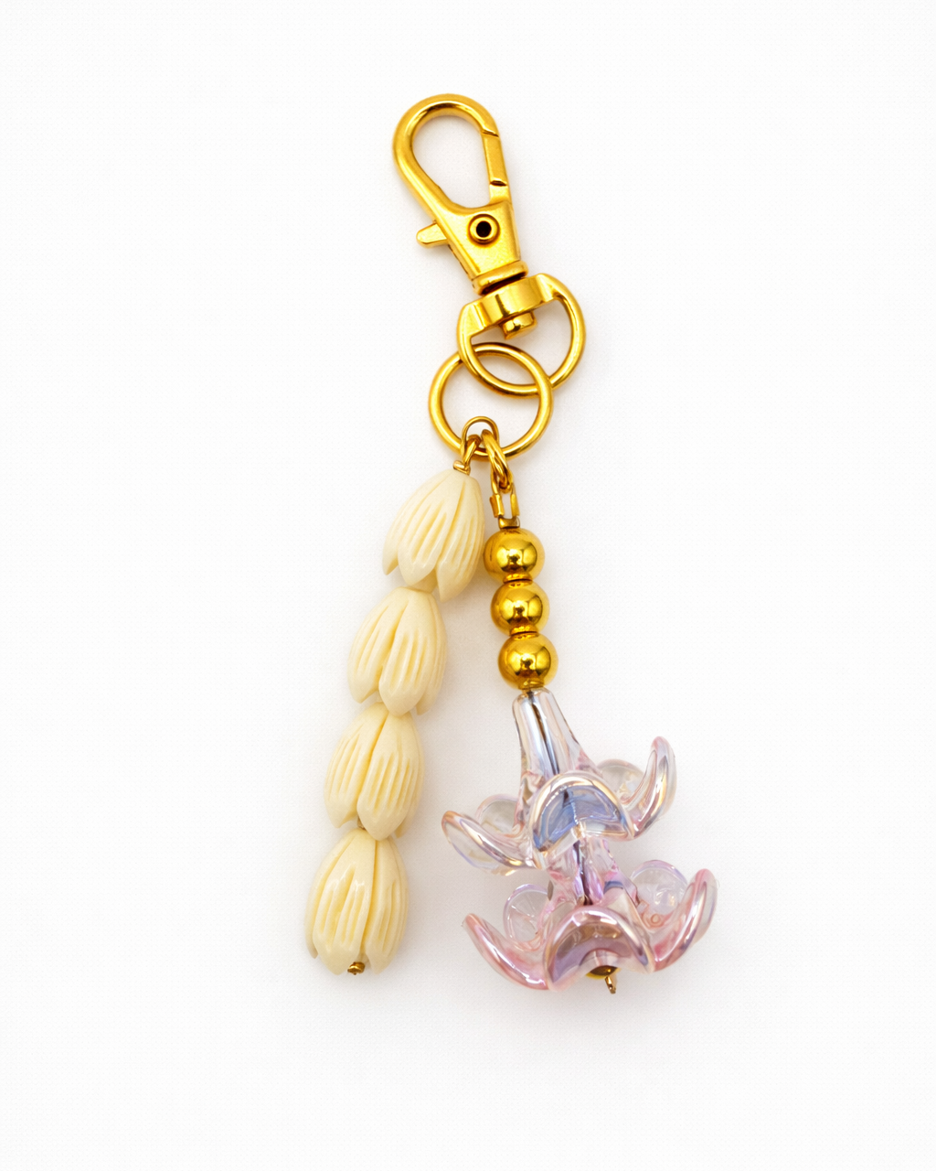 Decorative keychain with gold and beige beads and a pink flower charm on a white background